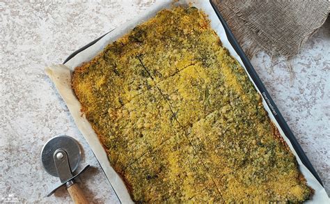 Schiacciata di broccoli dorata e croccante, tagliata a quadrotti, con olive