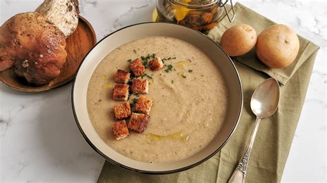 Un piatto elegante con seppioline saltate adagiate su una crema di funghi porcini, guarnito con erbe aromatiche.