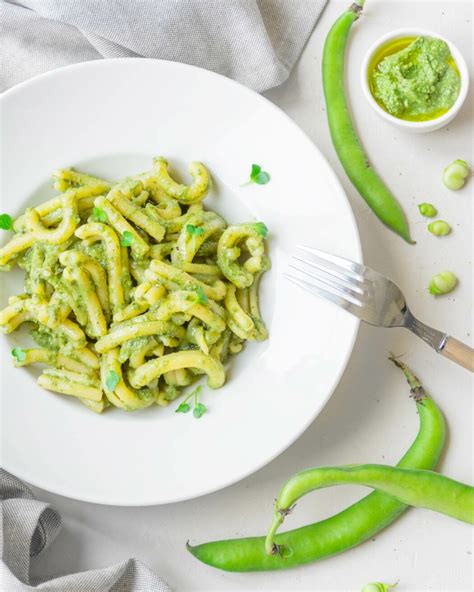 Immagine di baccelli di fave grigliati serviti con una salsa verde aromatica.
