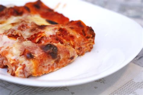 Primo piano di una porzione di lasagna con stracchino filante.
