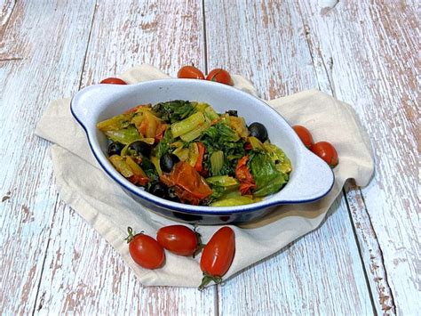 Verdure (carciofi, lattuga, pomodorini) che appassiscono in padella con cipolla.