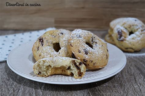 Una ciotola piena di ciambelline di farro dorate, alcune inzuppate nel vino rosso, altre con una spolverata di zucchero.