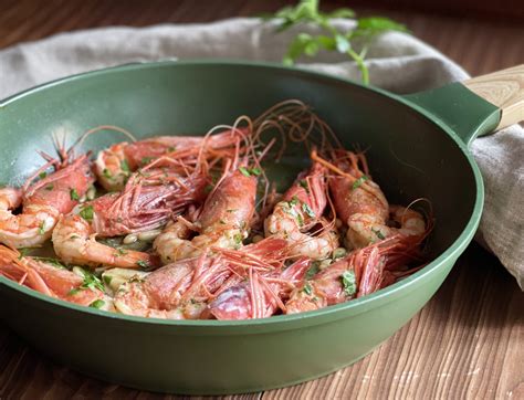 Padella con gamberi, aglio e peperoncino che sfrigolano, creando la base della salsa.