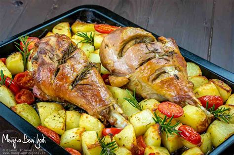Una placca da forno con la coscia d'agnello mentre cuoce, circondata da rosmarino e aglio.