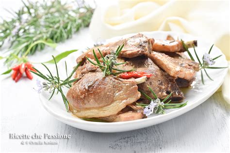 Un primo piano dei cubetti di agnello che rosolano in padella con aglio e rosmarino.