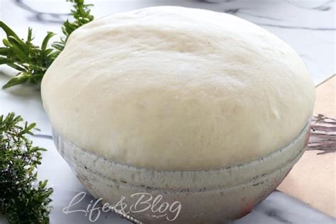 Primo piano di un impasto per focaccia che lievita in una ciotola, con bollicine visibili.