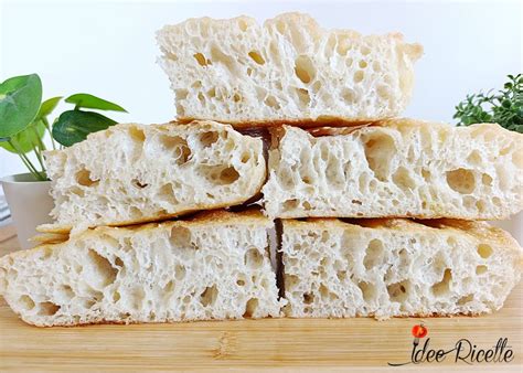 Focaccia lievitata in teglia, con bolle evidenti sulla superficie, pronta per l'affondo.
