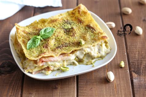 Una pirofila di lasagne bianche con pistacchio e mortadella, decorate con granella di pistacchio.