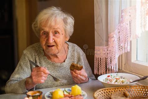 Illustrazione di una donna anziana che mangia pane con marmellata di prugne, evocando ricordi.
