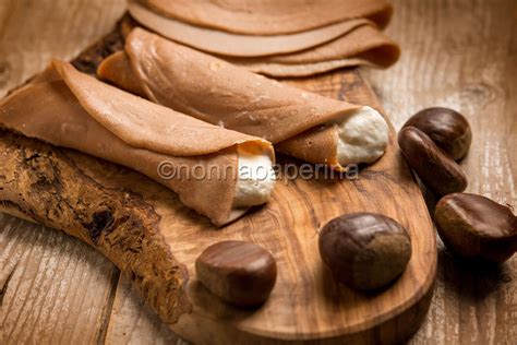 Gruppo di necci toscani appena preparati, alcuni arrotolati e farciti con ricotta, disposti su un piatto da portata.