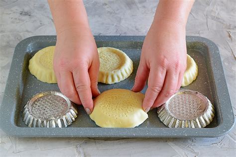 Disposizione dei dischi di pasta sfoglia negli stampini da muffin, precedentemente bucherellati.