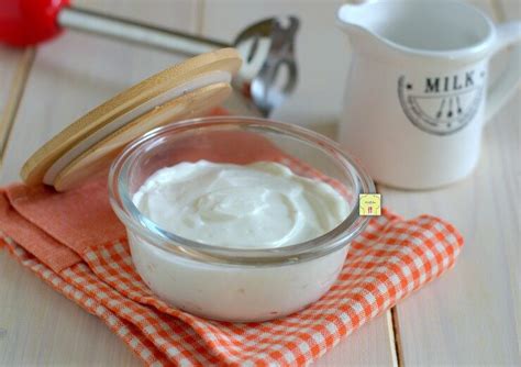 Una ciotola di panna da cucina bianca e liscia, con un mestolo che ne preleva una piccola quantità, mostrando la sua texture cremosa.