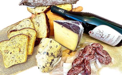 Foto di una selezione di prodotti tipici marchigiani e umbri, come prosciutti, formaggi, lenticchie e tartufi.