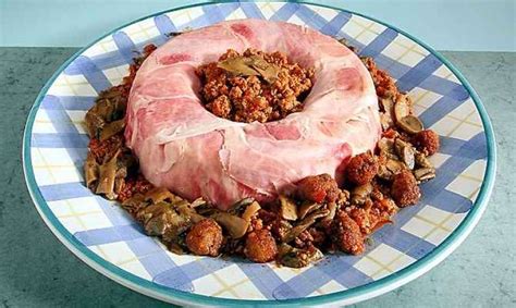 Immagine di un savarin di riso pronto, guarnito con polpette e sugo, su un elegante piatto da portata.