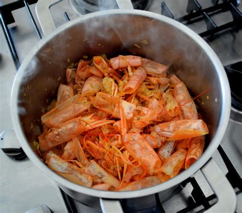 Brodo di crostacei che sobbolle in una pentola, preparato con teste e carapaci di scampi.