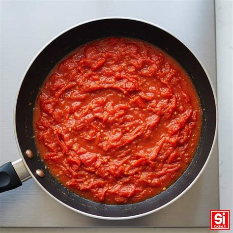 Padella con il sugo di pomodoro e scampi che cuoce a fuoco lento.