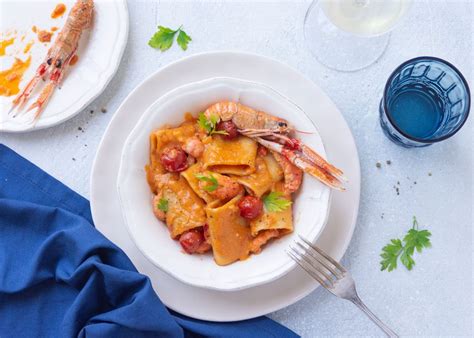 Paccheri che vengono mantecati nella padella con il sugo di scampi e frutti di mare.