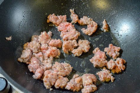 Salsiccia sbriciolata che rosola in padella con aglio e peperoncino