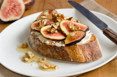 Primo piano di una bruschetta con formaggio di capra fuso, fichi caramellati e un filo di miele