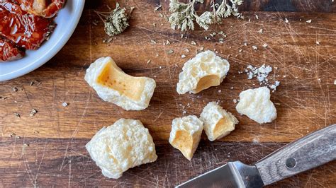 Primo piano di un cubetto di formaggio grana quasi fuso in un minestrone