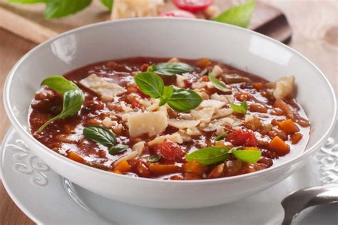 Un piatto di minestrone pronto per essere servito, guarnito con parmigiano e crostini