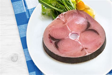 Primo piano di un trancio di pesce spada cotto che si sfalda con una forchetta