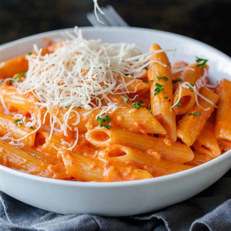 Una ciotola di penne alla vodka, con il sugo rosa cremoso e foglie di basilico fresco.