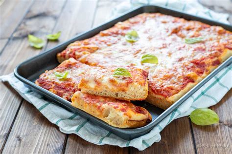 Immagine di una teglia con strati di pane, formaggio e erbe prima della cottura.