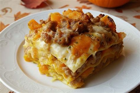 Immagine di una lasagna autunnale servita in una teglia, con strati visibili di pasta, zucca, funghi e besciamella, guarnita con rosmarino fresco.