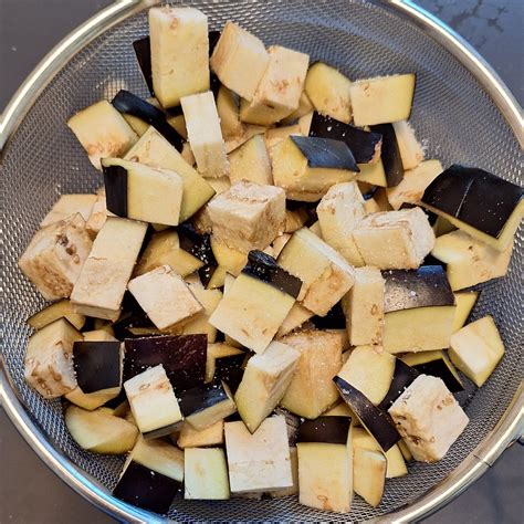 Melanzane tagliate a cubetti e pomodorini pronti per la cottura nel tegame