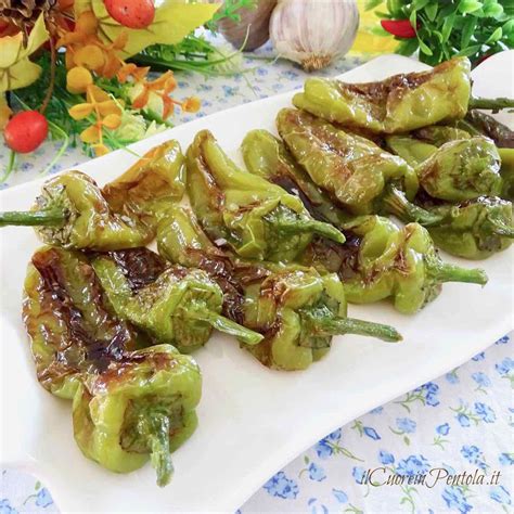 Primo piano di friggitelli che vengono fritti in una padella con olio bollente.