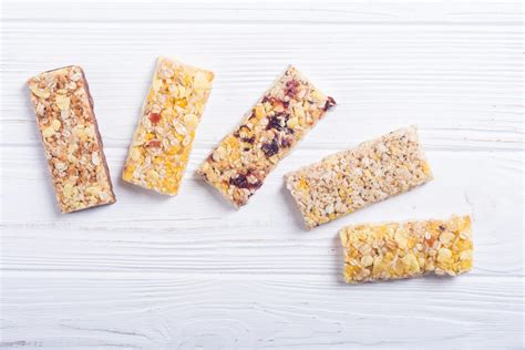 Varietà di ingredienti secchi per barrette ai cereali: fiocchi d'avena, frutta secca, semi e gocce di cioccolato.