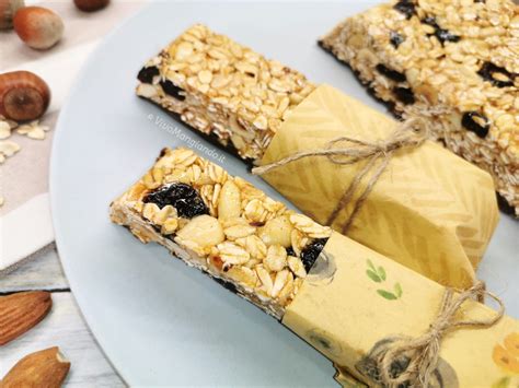 Composto di cereali e frutta secca steso su carta da forno in una teglia rettangolare, pronto per la cottura.