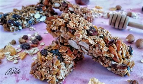 Barrette ai cereali fatte in casa guarnite con gocce di cioccolato e noci, su un piano di lavoro.