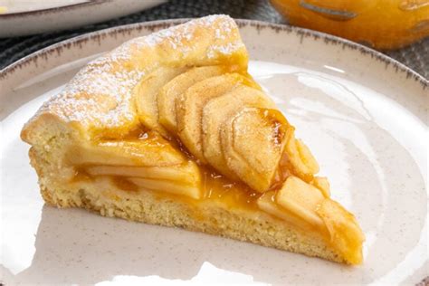 Una crostata chiusa dorata con un ripieno visibile di mele e marmellata