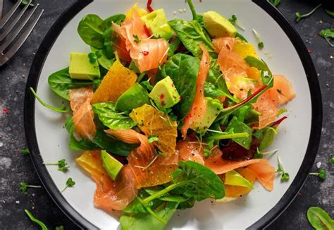 Insalata mista con salmone affumicato, formaggio di capra, mandorle e sedano, presentata in modo invitante.