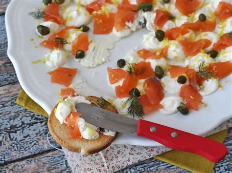 Primo piano di salmone affumicato servito con una crema di formaggio al limone e crostini croccanti.