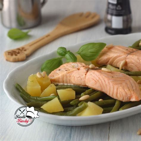 Fotografia di un piatto con filetto di salmone grigliato e fagiolini saltati, guarnito con limone e prezzemolo.