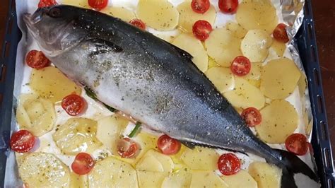 Ricciola intera al forno in una teglia con pomodorini e patate