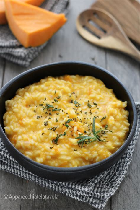 Una porzione di risotto alla zucca vegano servito in una ciotola, guarnito con erbe aromatiche fresche.