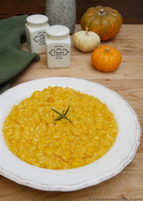 Un primo piano degli ingredienti freschi per il risotto: zucca a cubetti, riso Carnaroli, cipolla, erbe aromatiche.
