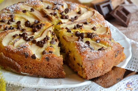 Immagine di pancake soffici con pere a pezzetti e gocce di cioccolato che fuoriescono dall'impasto, disposti su un piatto rustico con una tazza di tè fumante sullo sfondo, in un'ambientazione autunnale con foglie secche.