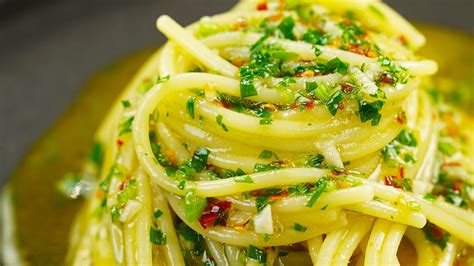 Immagine di un piatto fumante di spaghetti aglio, olio e peperoncino guarniti con prezzemolo fresco.