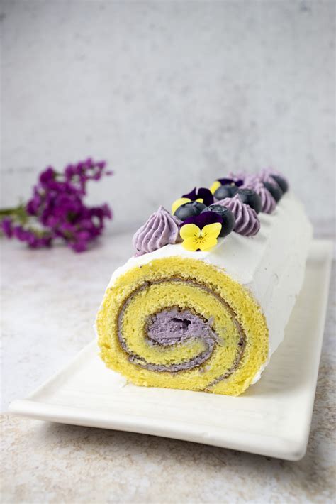 Piatto finito di rotolo dolce con crema al mascarpone e mirtilli, decorato con fiori eduli.