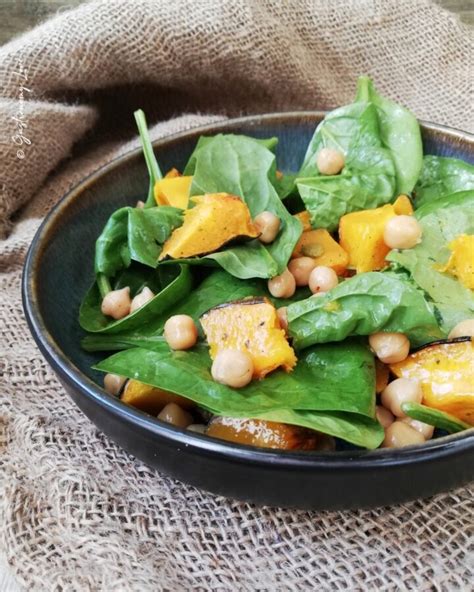 Composizione di insalata autunnale con zucca arrosto, spinacini freschi e mandorle tostate