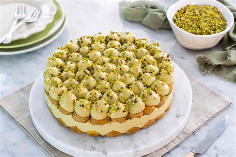 Primo piano di una tortina al pistacchio durante la fase di copertura con cioccolato fondente, utilizzando uno stecco da spiedino.