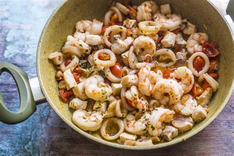 Foto ravvicinata di pomodorini che cuociono con il misto di pesce in padella