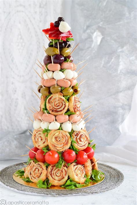 Una composizione di diversi antipasti a forma di alberello natalizio su un piatto da portata decorato.