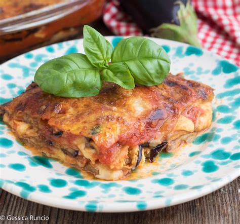 Strati di parmigiana di melanzane in una pirofila, con melanzane, sugo, mozzarella e parmigiano.