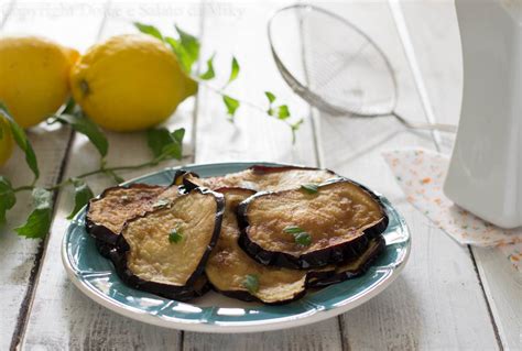 Fette di melanzane dorate fritte in padella, pronte per essere scolate su carta assorbente.